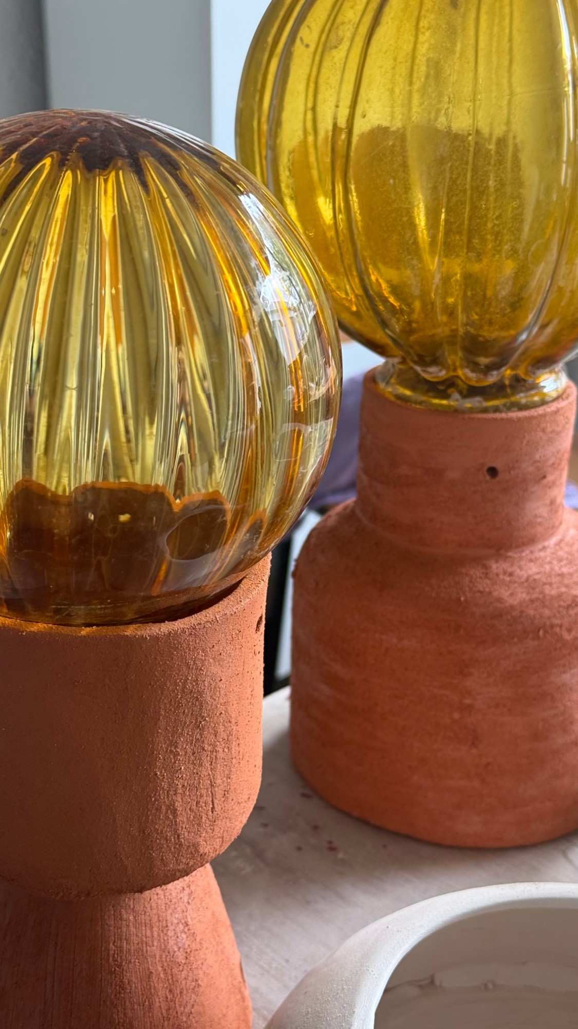 Tulipas de vidrio ámbar recuperado sobre bases de cerámica cruda, de la cápsula La forma del ahora